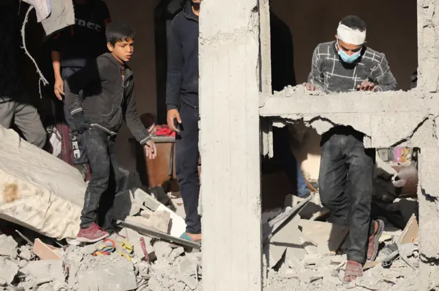 فلسطينيون يفحصون موقع غارة جوية إسرائيلية على منزل، وسط استمرار الصراع بين إسرائيل وحماس، في مدينة غزة.