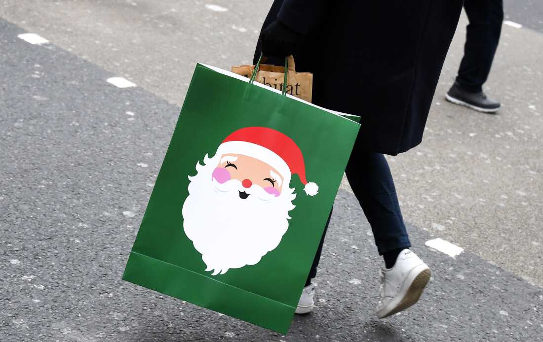 A shopper carries a Christmas-themed bag in London on Dec. 2, 2020.