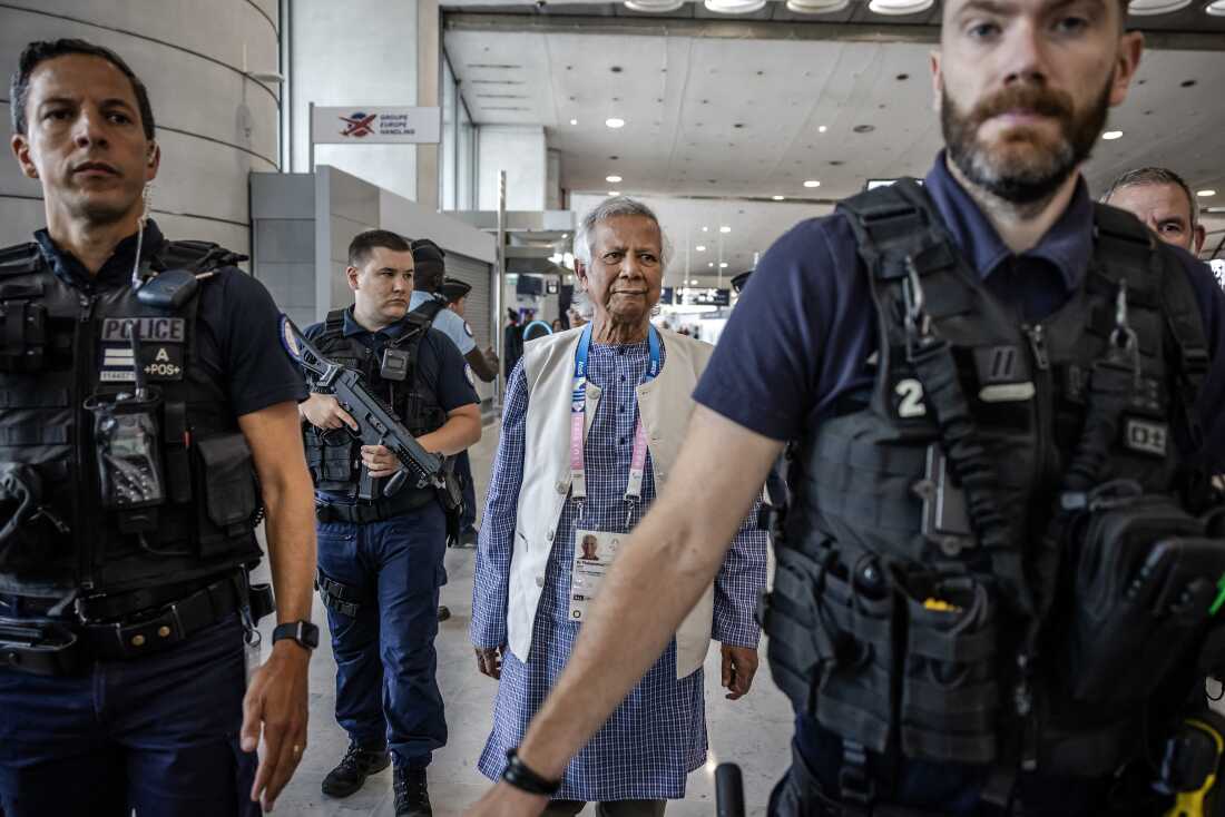 Bangladeshi finance pioneer Muhammad Yunus is escorted by French police personnel as he arrives at Charles de Gaulle Airport, north of Paris.