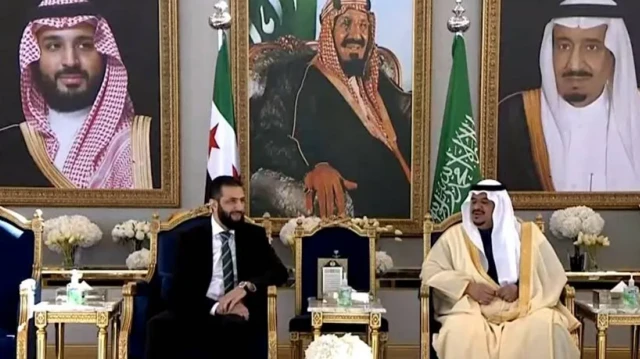 نائب أمير الرياض مرتدياً لباساً تقليدياً سعودياً وخلفه العلم السعودي وإلى جانبه الشرع مرتدياً بدلة رسمية سوداء وربطة عنق