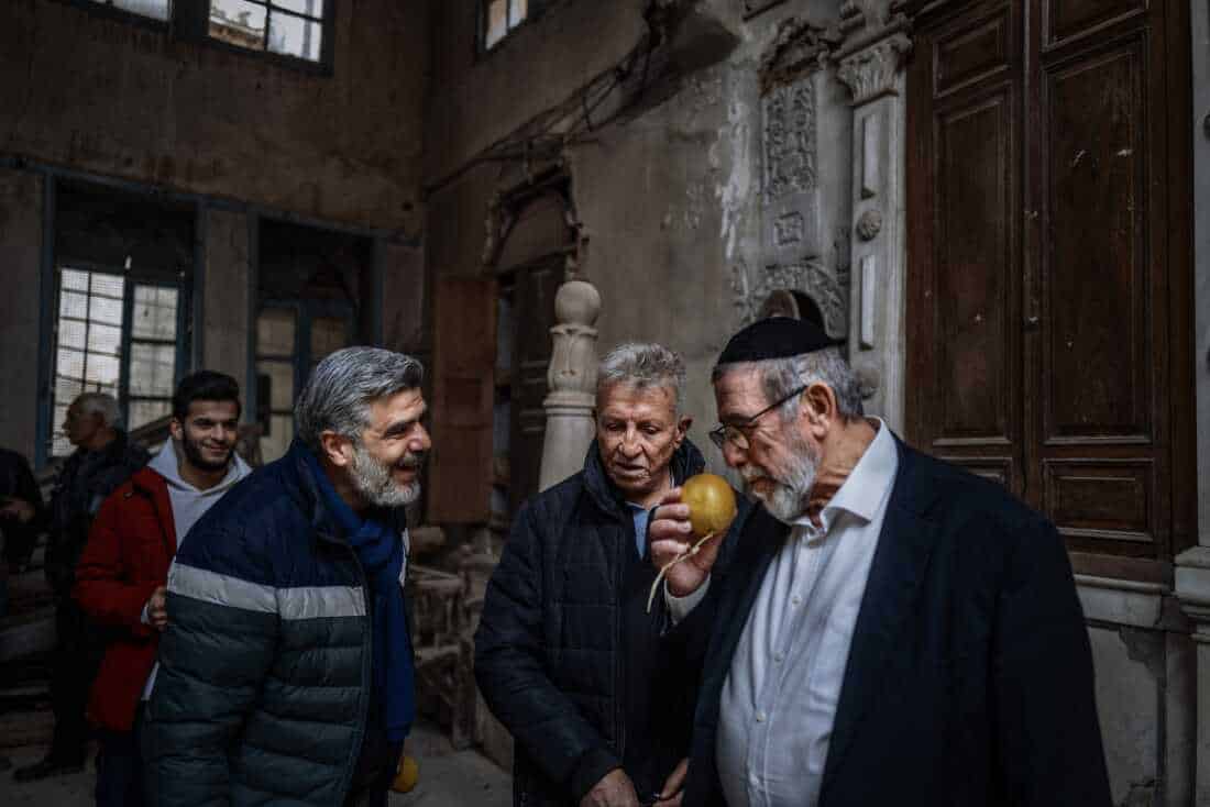DAMASCUS, Syria, 02/19/25 Rabbi Yousif Hamra smells a citrus fruit with former neighbors in Old Damascus. . Ayman Oghanna for NPR