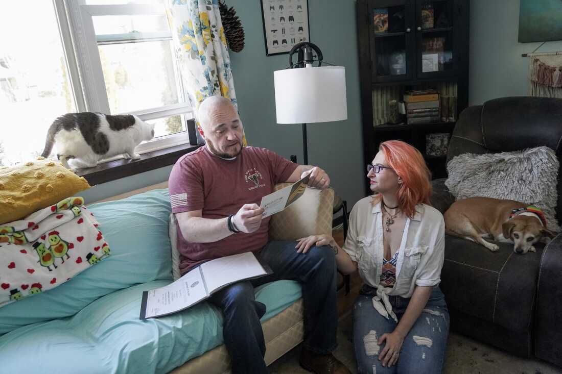 Kevin and Jenny Conlon look through Kevin’s scrapbook from his time in Iraq in their living room. Their white and gray cat Spaz and Beagle Paisely join them. 
