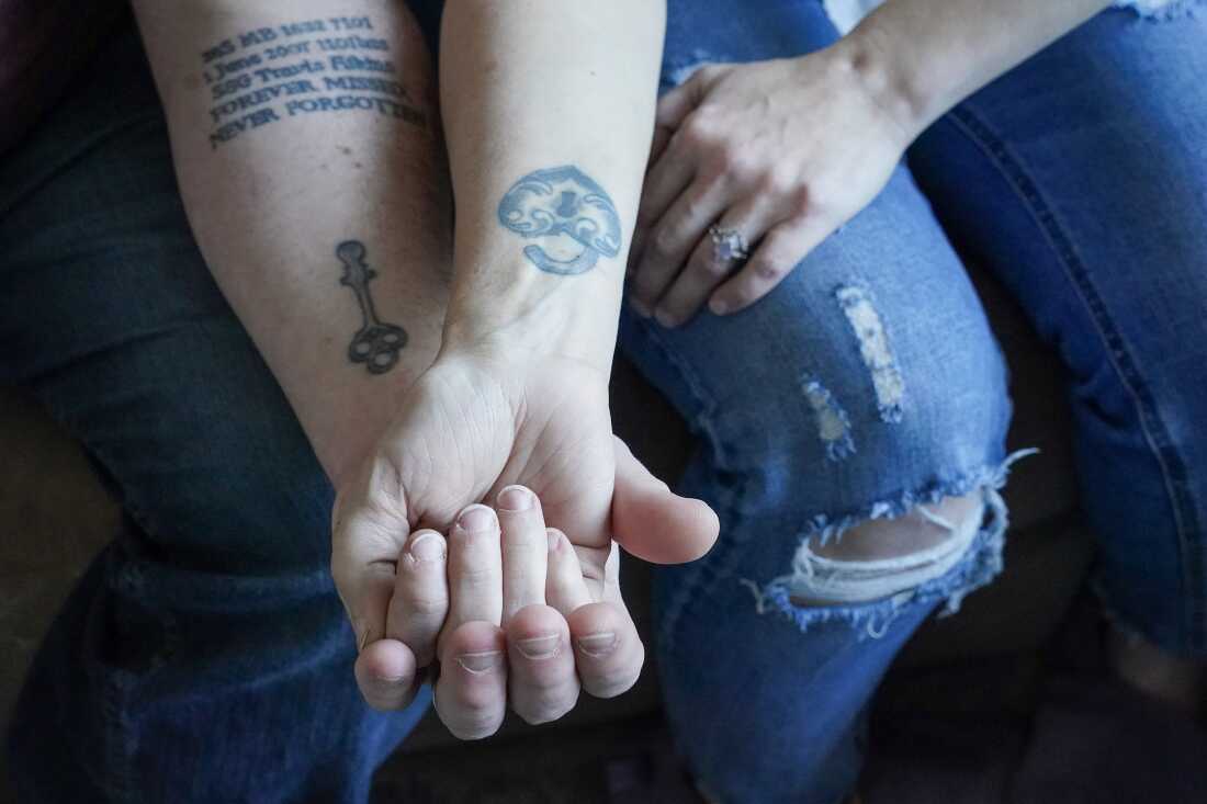 Kevin and Jenny Conlon hold hands as show their lock and key tattoos on the inside of their forearms. Kevin has the key and Jenny's lock is shaped like a heart.