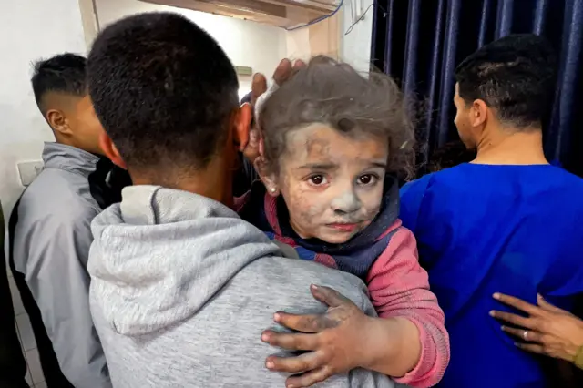 رجل فلسطيني يحمل طفلة مصابة إلى مستشفى المعمداني الأهلي، بعد غارة إسرائيلية على حي الشجاعية في مدينة غزة، 9 أبريل/نيسان 2025