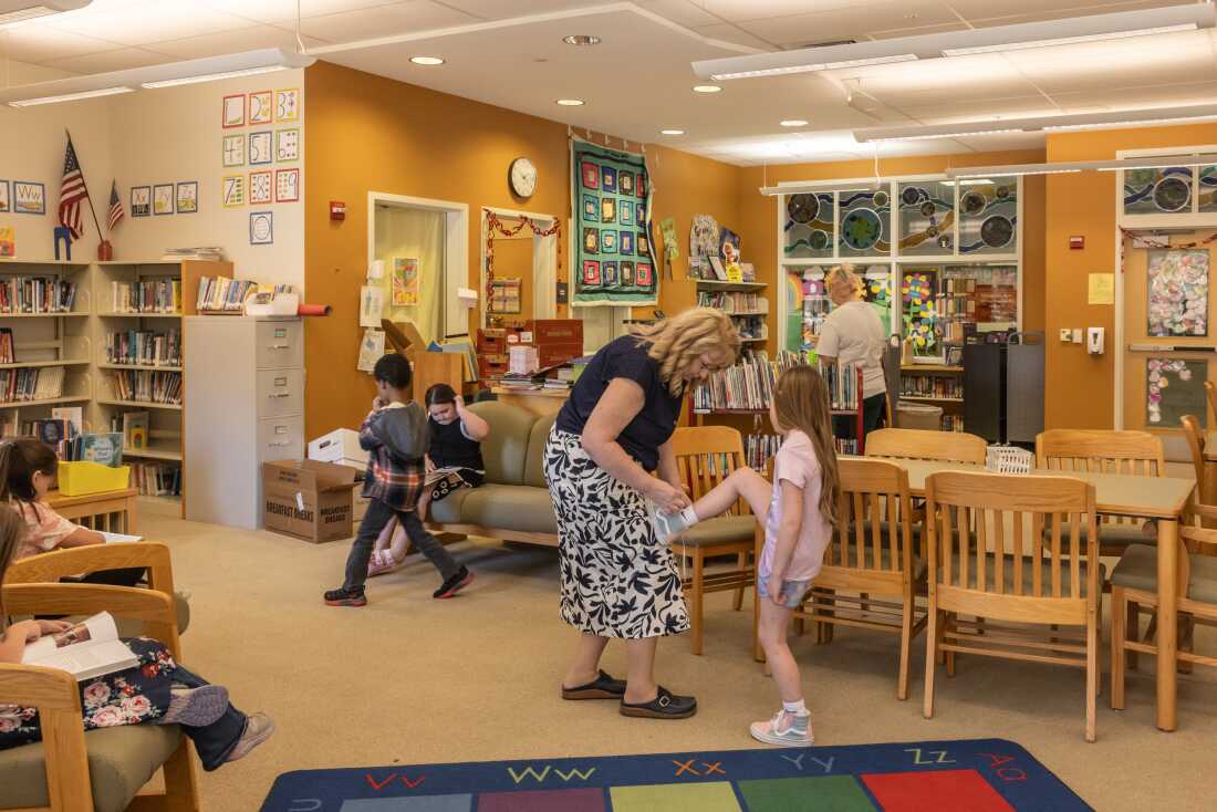 Barbara Welch has been an educator in the MSAD 54 district for nearly four decades. She helps a student tie their shoe in the library of Mill Stream.