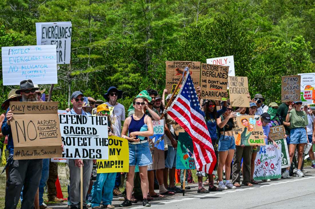 Demonstrators hold signs as they protest the construction of "Alligator Alcatraz" on Saturday.