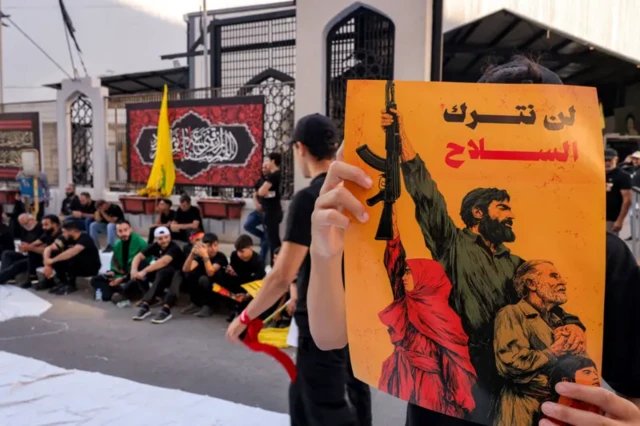 صورة من مظاهرة مؤيدة لحزب الله ويبدو فيها شخص يحمل لافتة مكتوباً عليها: "لن نترك السلاح".