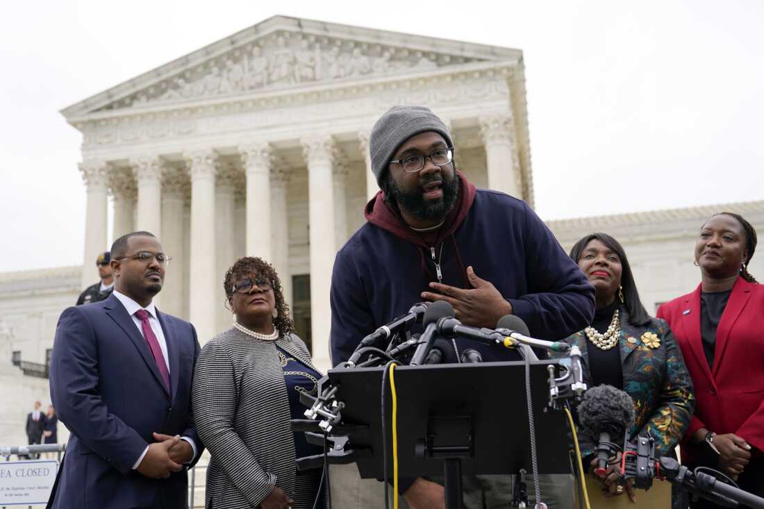 Evan Milligan (center) speaks outside the U.S. Supreme Court in Washington, D.C., in 2022 after the justices heard oral arguments in the voting rights lawsuit he and other Black voters filed over Alabama’s congressional voting map.