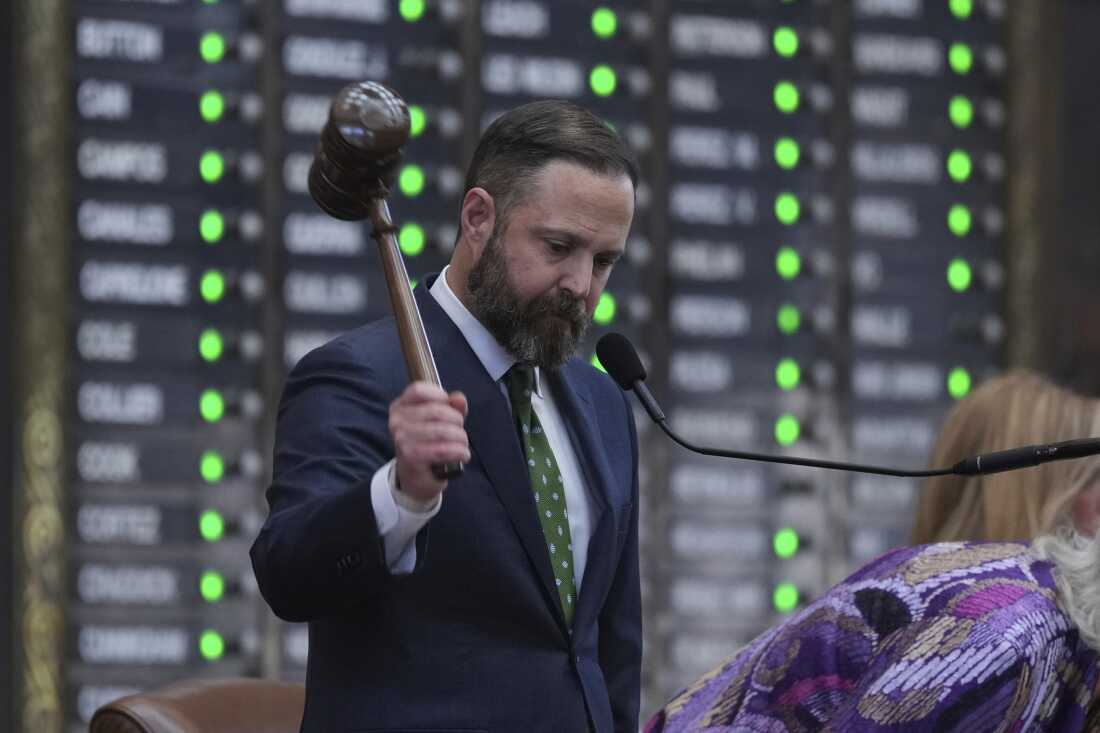Standing in front of a microphone, Texas House Speaker Dustin Burrows strikes a large gavel in July 2025.