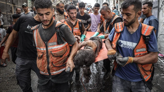 منقذون يحملون طفلا بعد إنقاذه من بين الأنقاض بعد هجوم إسرائيلي على مدينة غزة، 16 سبتمبر/أيلول 2025. 
