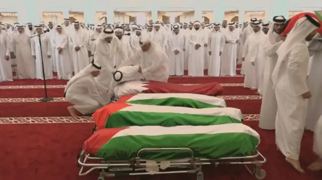 حشود تُشيّع جثامين ضحايا الهجوم الإسرائيلي على الدوحة في مسجد الشيخ محمد بن عبد الوهاب في الدوحة. لفت ثلاثة جثامين بالعلم الفلسطيني والجثمان الرابع لف بالعلم القطري. والمشيعون الظاهرون في الصورة بأعداد كبيرة يرتدون اللباس الخليجي التقليدي الأبيض.