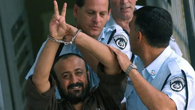 صورة أرشيفية لمروان البرغوثي مكبلاً ورافعاً إشارة النصر، أثناء اقتياد الشرطة الإسرائيلية له.