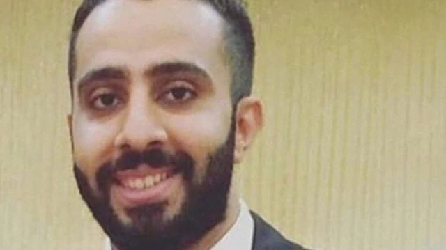 المعارض البحريني علي الشويخ مرتديا بذلة رسمية وخلفه حائط أصفر اللون