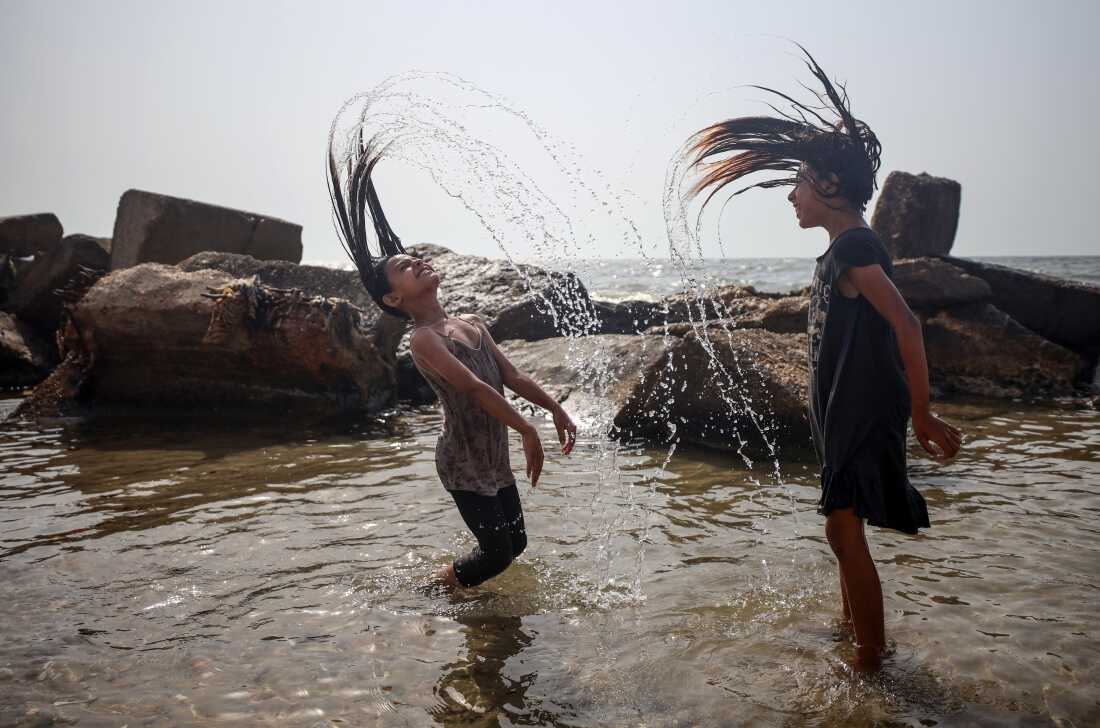 Palestinian children play in the shallow water along the shoreline to cool off from a heat wave on a beach in Gaza City, on August 13, 2025. (Photo by Majdi Fathi/NurPhoto via Getty Images)