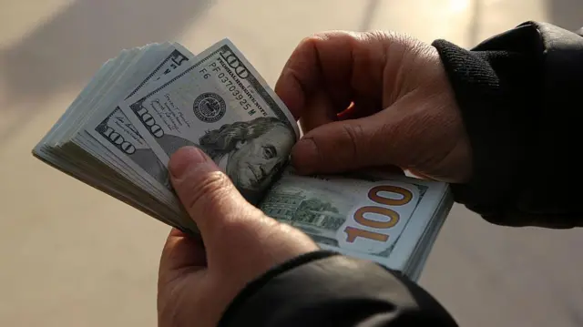 شخص يمسك دولارات ويعدها