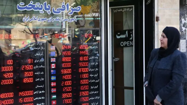 سيدة إيرانية تقف أمام محل صرافة في العاصمة طهران تراقب أسعار صرف العملات الأجنبية 