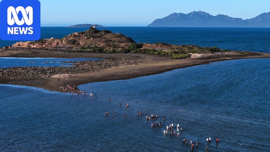 People walking to North Head Island lighthouse across exposed seabed at Bowen during ultra-low winter tides